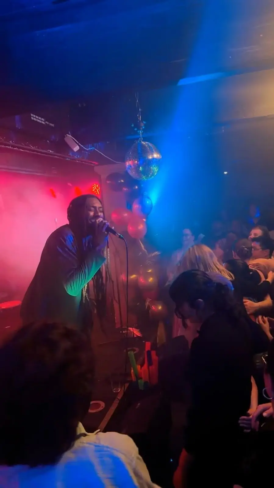 A singer performs under blue and pink club lights at a WaawAfrica night