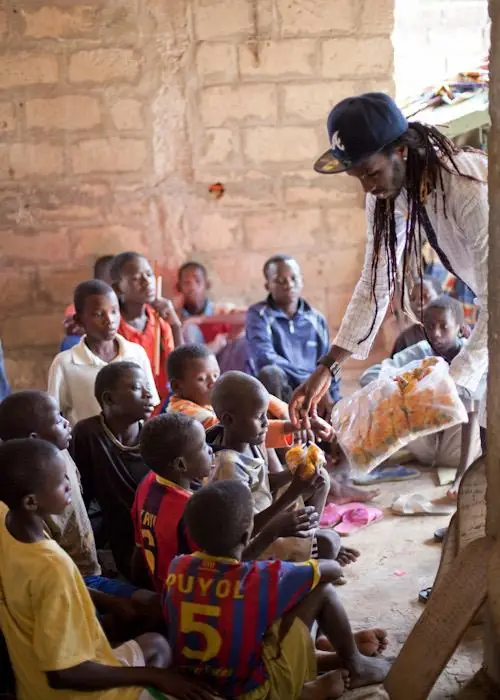 Vapaaehtoinen jakaa tarvikkeita lapsille Senegalissa