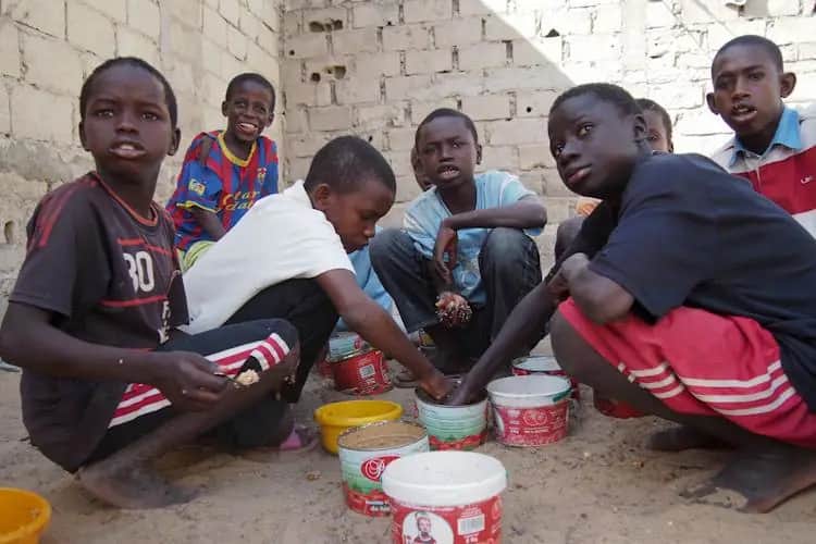 Children share food together from bowls on the ground