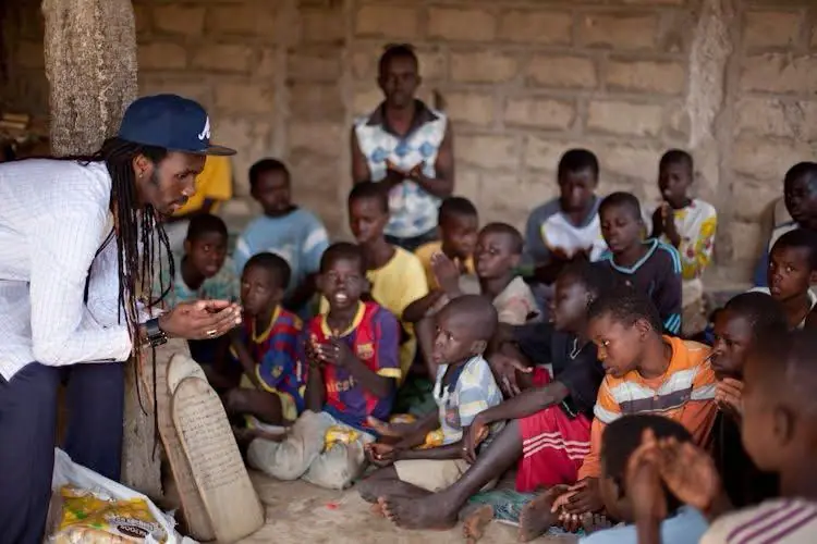 Vapaaehtoinen juttelee yhdessä istuvan lapsiryhmän kanssa Senegalissa